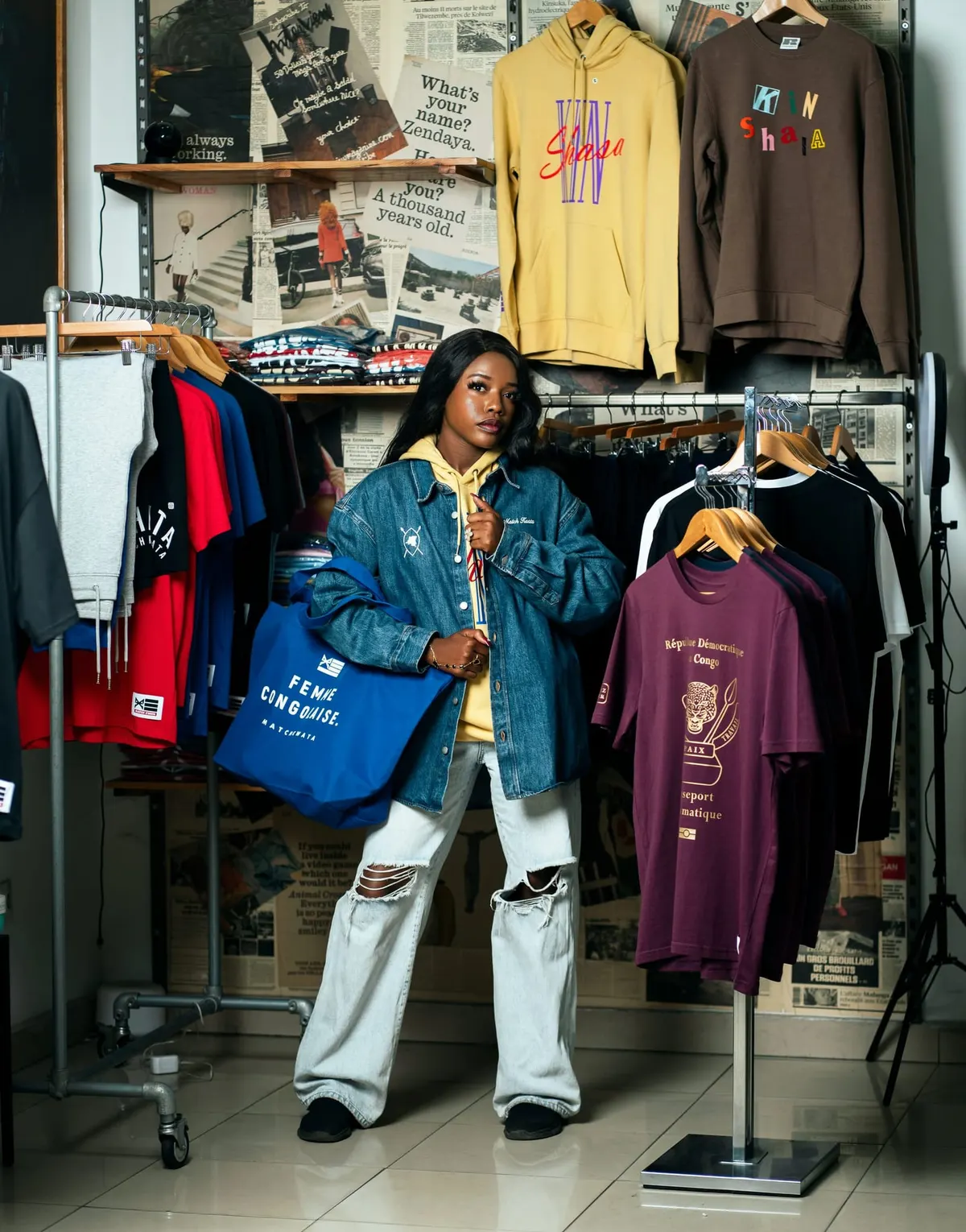 Une cliente en veste en jean Match Kwata, tote bag Femme congolaise à la main, dans la boutique de Kinshasa